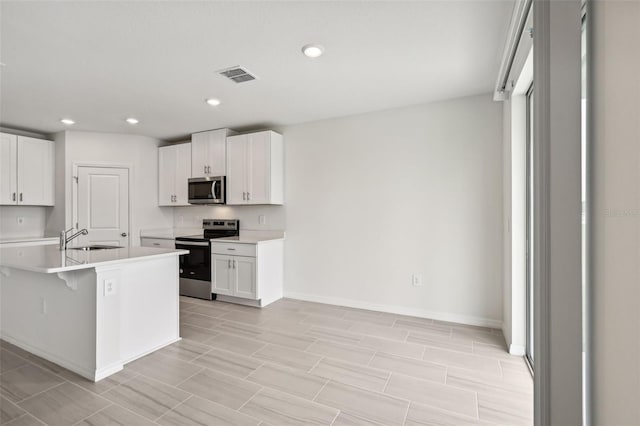 kitchen with stainless steel appliances, white cabinets, sink, and a breakfast bar