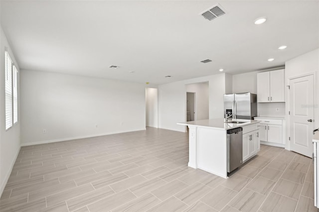 kitchen featuring an island with sink, white cabinets, and appliances with stainless steel finishes