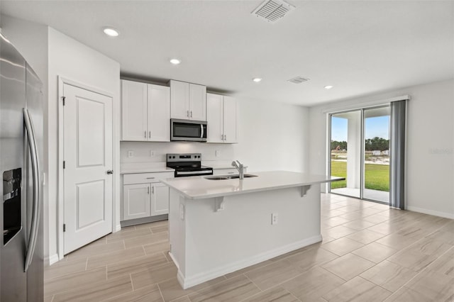 kitchen featuring a kitchen island with sink, stainless steel appliances, sink, and white cabinets