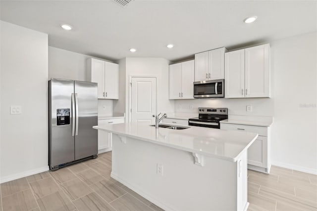 kitchen featuring a center island with sink, sink, white cabinetry, and appliances with stainless steel finishes