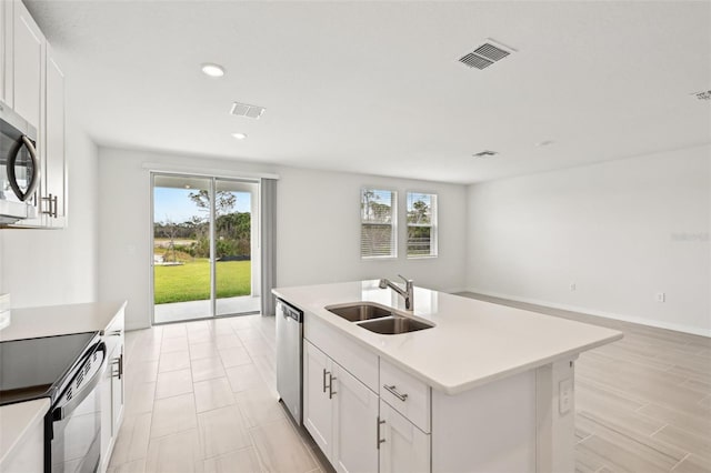 kitchen with an island with sink, white cabinetry, sink, and a healthy amount of sunlight