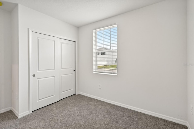 unfurnished bedroom with light colored carpet and a closet