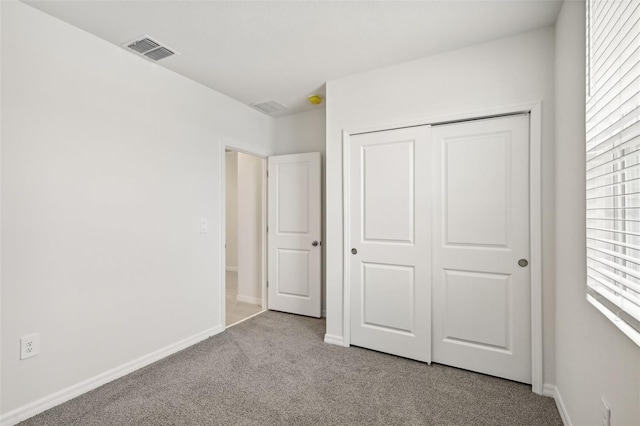 unfurnished bedroom with light carpet and a closet