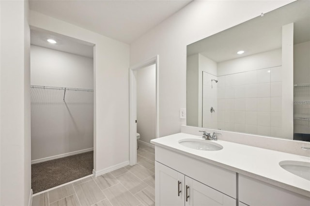 bathroom featuring toilet, vanity, and tiled shower