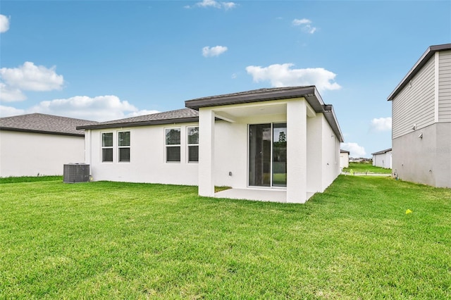 rear view of house with central air condition unit and a lawn