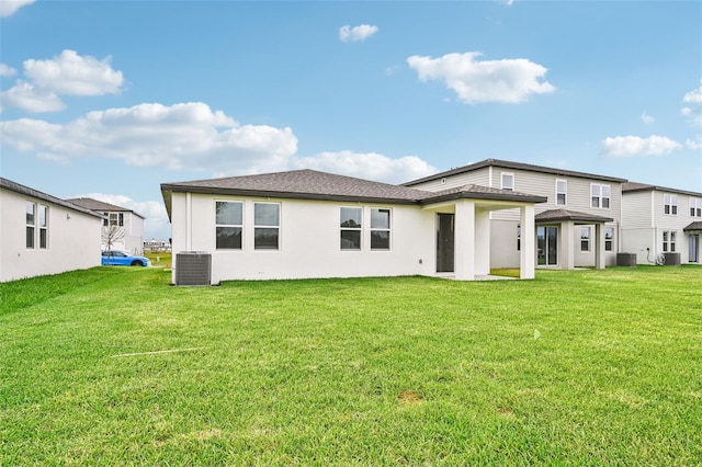 rear view of property with central air condition unit and a lawn