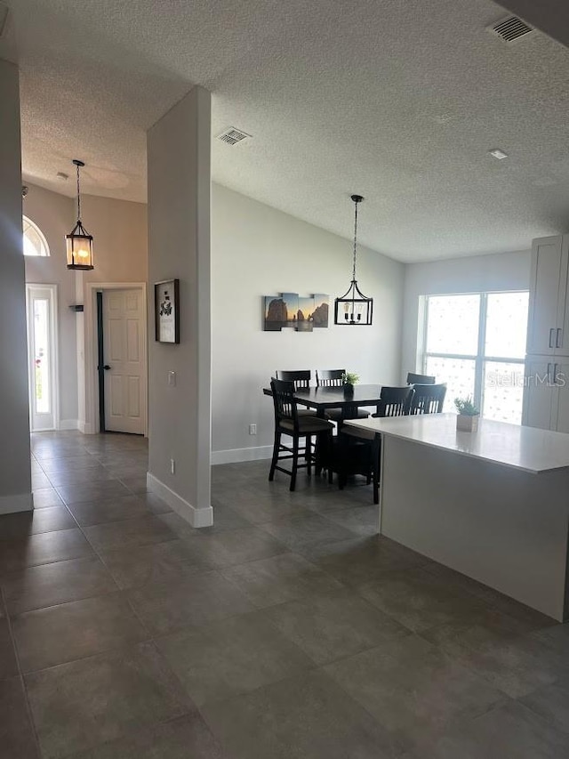 dining space with a textured ceiling, lofted ceiling, and a chandelier