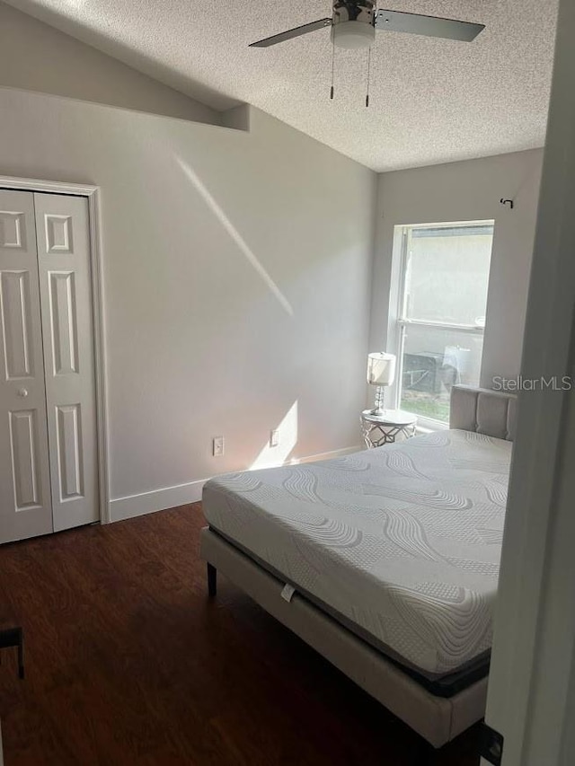 bedroom with a closet, ceiling fan, dark wood-type flooring, and a textured ceiling