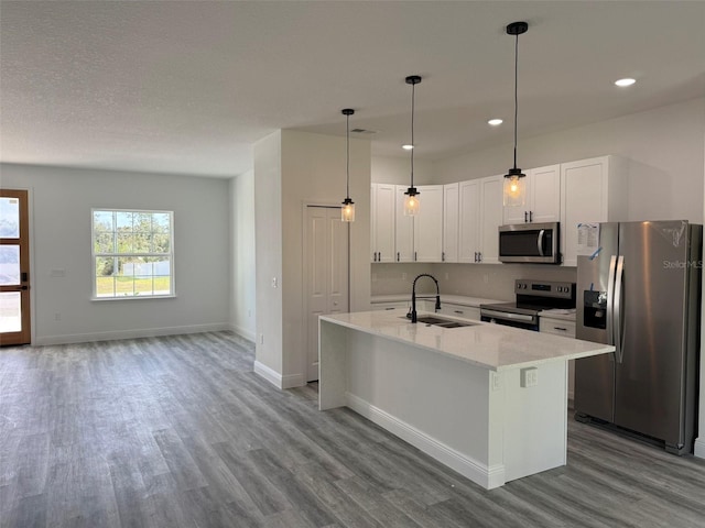 kitchen featuring a kitchen island with sink, sink, appliances with stainless steel finishes, light hardwood / wood-style floors, and white cabinetry