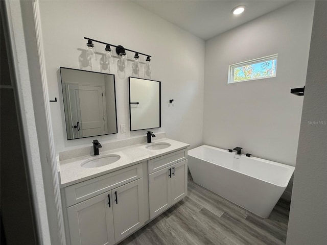 bathroom with hardwood / wood-style floors, a bathtub, and vanity