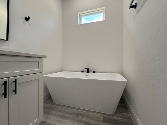 bathroom with a bathing tub, vanity, and wood-type flooring