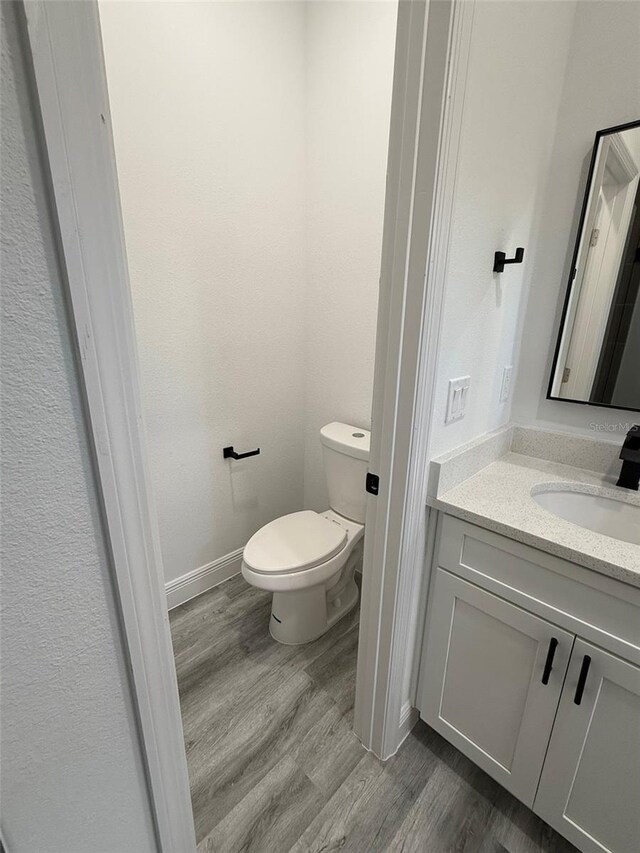 bathroom with hardwood / wood-style floors, vanity, and toilet