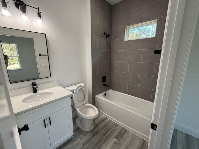 full bathroom with hardwood / wood-style floors, vanity, toilet, and tiled shower / bath