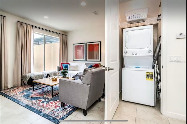 laundry area featuring stacked washer / drying machine and light tile patterned flooring