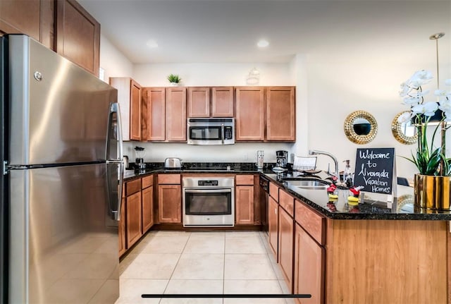 kitchen with sink, light tile patterned flooring, kitchen peninsula, stainless steel appliances, and dark stone countertops