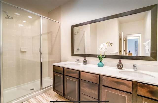 bathroom featuring a shower with door and vanity