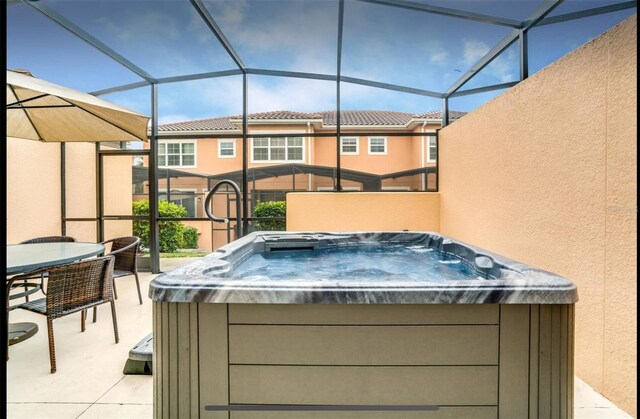 view of patio with a hot tub and glass enclosure