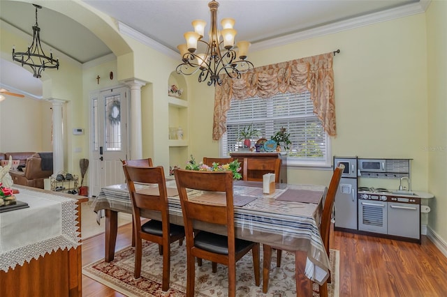 dining room with dark hardwood / wood-style floors, crown molding, decorative columns, and a notable chandelier