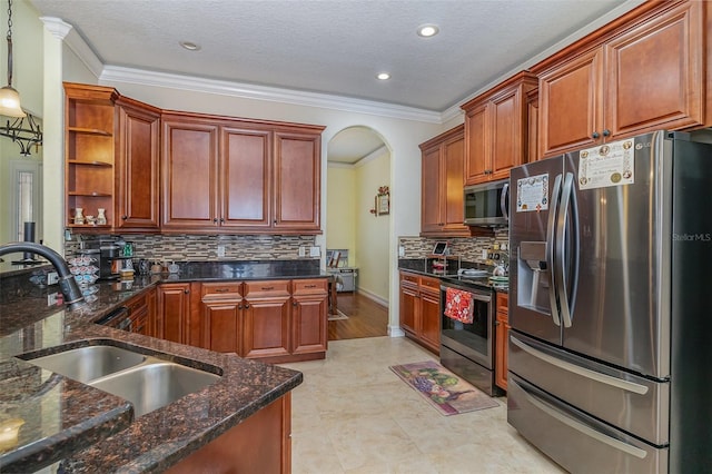 kitchen with pendant lighting, dark stone counters, crown molding, sink, and stainless steel appliances