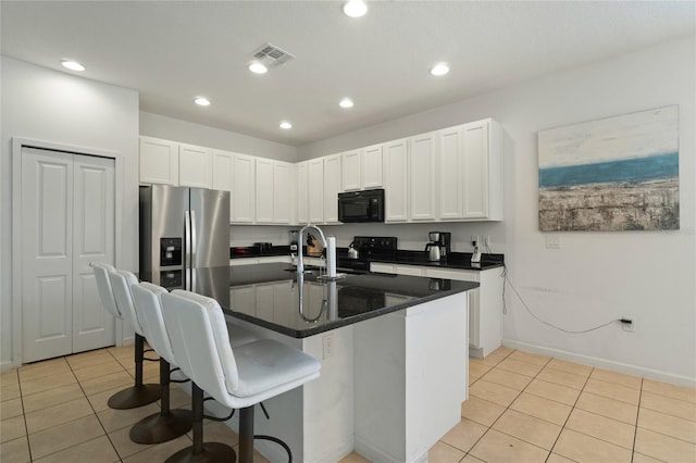 kitchen featuring a center island with sink, a breakfast bar, white cabinetry, black appliances, and sink