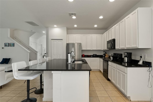 kitchen featuring white cabinets, an island with sink, a kitchen bar, black appliances, and sink