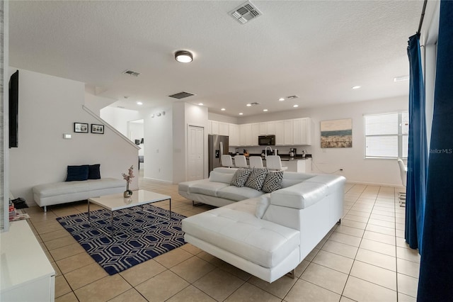 living room featuring a textured ceiling and light tile patterned floors