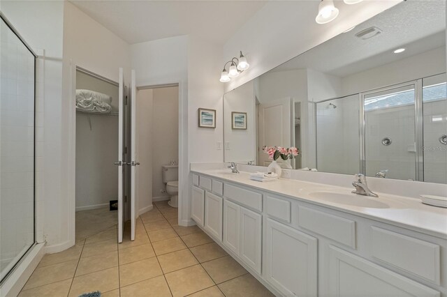 bathroom with vanity, tile patterned flooring, toilet, and walk in shower