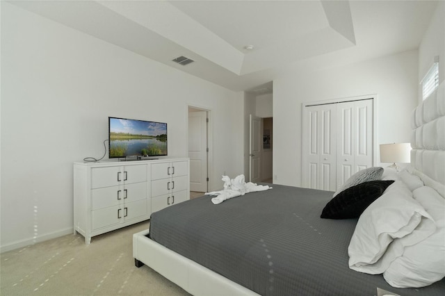 bedroom with light carpet, a closet, and a raised ceiling