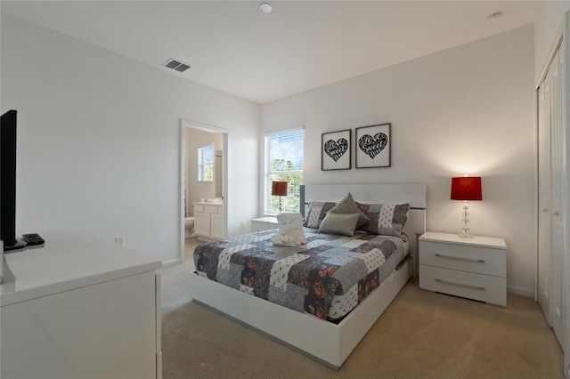 bedroom with light carpet and ensuite bath