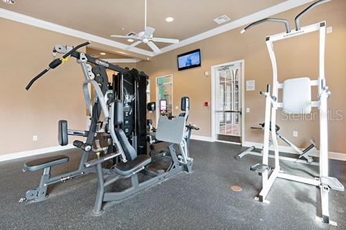 workout area featuring ceiling fan and ornamental molding