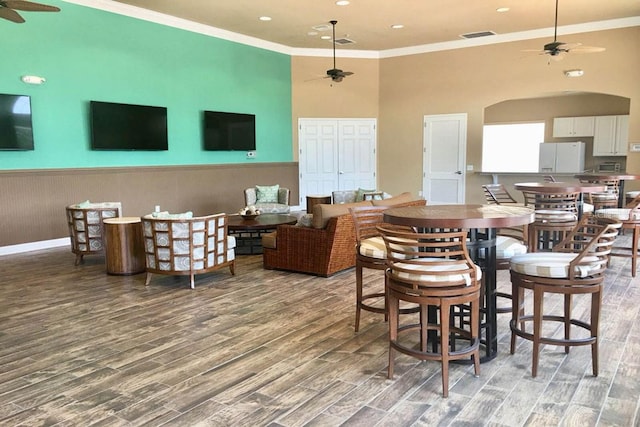 dining space with crown molding, wood-type flooring, a high ceiling, and ceiling fan