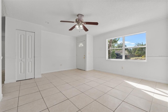 tiled empty room with ornamental molding, a textured ceiling, and ceiling fan