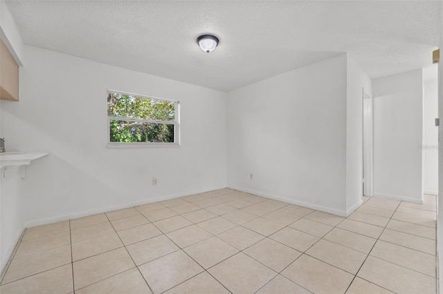 empty room featuring a textured ceiling and light tile patterned floors