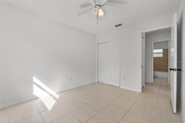 unfurnished bedroom with light tile patterned flooring, a closet, and ceiling fan