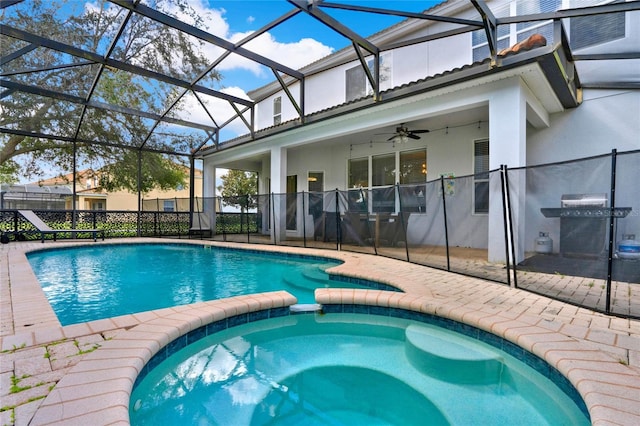 view of swimming pool featuring ceiling fan, glass enclosure, area for grilling, a patio, and an in ground hot tub