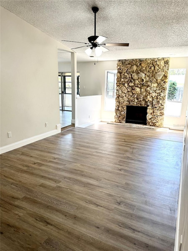 unfurnished living room with ceiling fan, dark hardwood / wood-style floors, a textured ceiling, and a fireplace