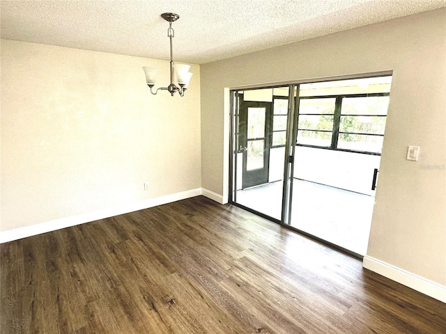 spare room with dark wood-type flooring, a chandelier, and a textured ceiling