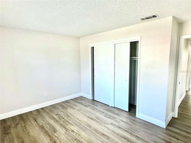 unfurnished bedroom featuring a closet, light wood-type flooring, and a textured ceiling