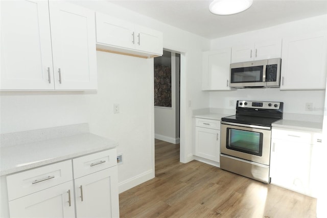 kitchen with white cabinets, stainless steel appliances, light wood-style floors, and light countertops