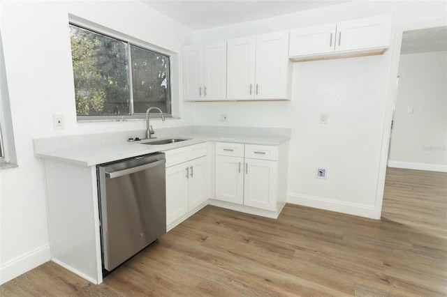 kitchen featuring white cabinets, light wood-style flooring, dishwasher, baseboards, and a sink