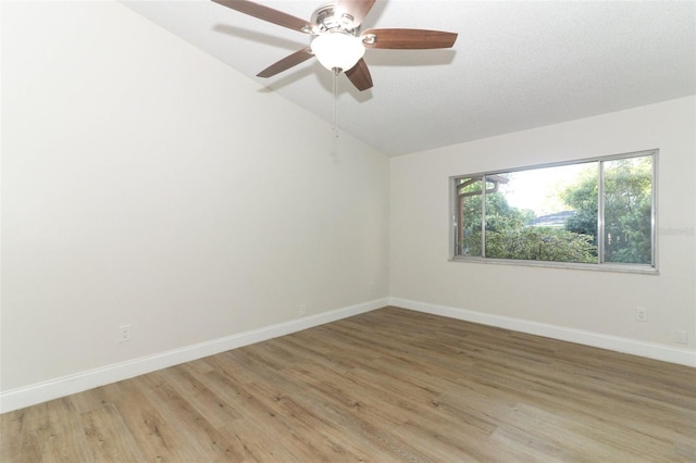 empty room featuring light wood finished floors, baseboards, lofted ceiling, and ceiling fan
