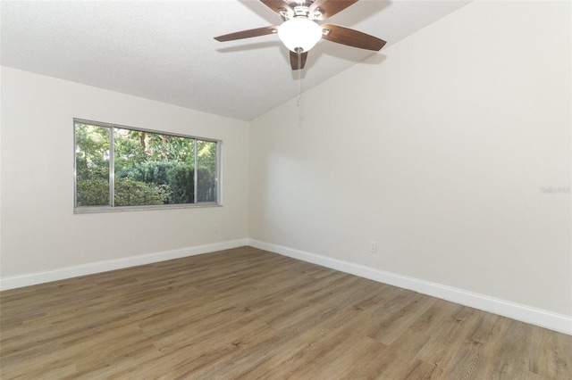 empty room featuring baseboards, lofted ceiling, light wood finished floors, and ceiling fan