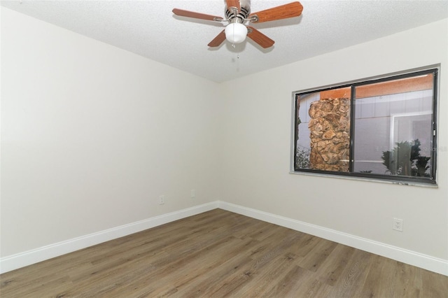 spare room with a ceiling fan, a textured ceiling, baseboards, and wood finished floors