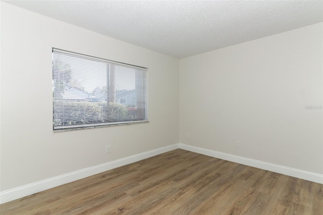 unfurnished room with a textured ceiling, baseboards, and light wood-type flooring