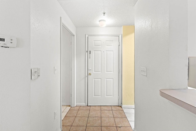 hall featuring a textured ceiling and light tile patterned floors