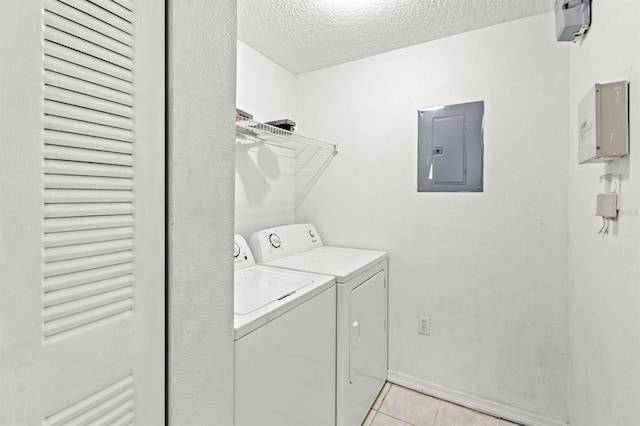 clothes washing area featuring a textured ceiling, electric panel, separate washer and dryer, and light tile patterned floors