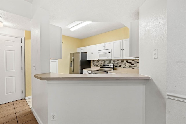 kitchen with tasteful backsplash, appliances with stainless steel finishes, kitchen peninsula, and white cabinets