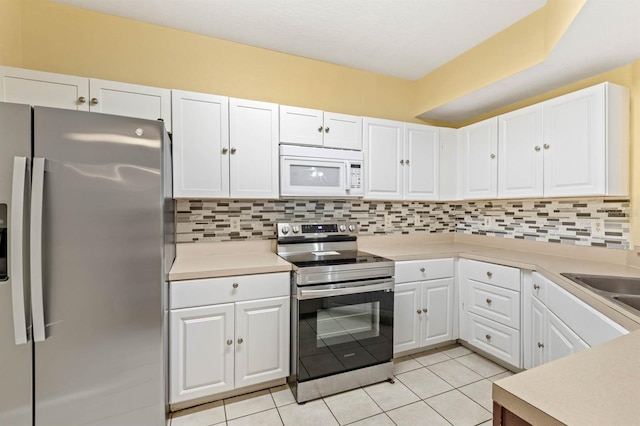 kitchen with appliances with stainless steel finishes, white cabinets, tasteful backsplash, and light tile patterned floors