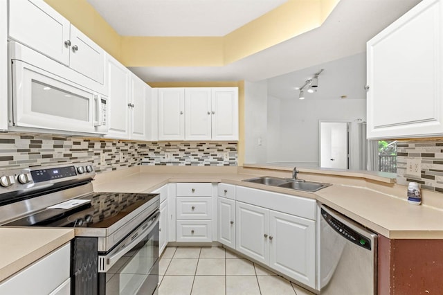 kitchen with kitchen peninsula, stainless steel appliances, sink, light tile patterned floors, and white cabinets