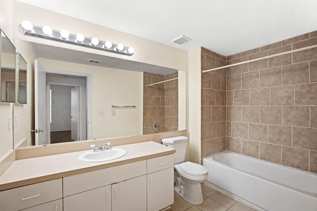 full bathroom with tiled shower / bath, a textured ceiling, toilet, vanity, and tile patterned flooring